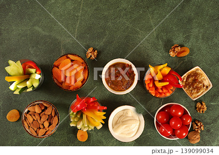 Middle East plate, Healthy food cuisine background with hummus bowl and raw vegetable sticks, nuts and dried apricots. Hummus platter with appetizers,traditional vegan snacks,oriental cuisine concept Middle East plate, Healthy food cuisine background with hummus bowl and raw vegetable sticks, nuts and dried apricots. Hummus platter with appetizers,traditional vegan snacks,oriental cuisine concept 139099034