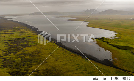 Aerial View of Icelandic River with Green Fields and Volcanic Soil Aerial View of Icelandic River with Green Fields and Volcanic Soil 139099817