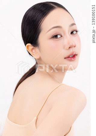 Beautiful young Asian woman with perfect glowing skin and ponytail hairstyle isolated on white background. High key portrait for beauty, skincare, and spa treatment commercial advertising. 139100151
