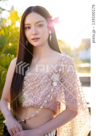 Trendy Thai fashion woman wearing a traditional Sabai paired with denim jeans at temple, reflecting the growing fashion trend in Thailand that blends cultural heritage with contemporary street style. Trendy Thai fashion woman wearing a traditional Sabai paired with denim jeans at temple, reflecting the growing fashion trend in Thailand that blends cultural heritage with contemporary street style. 139100179