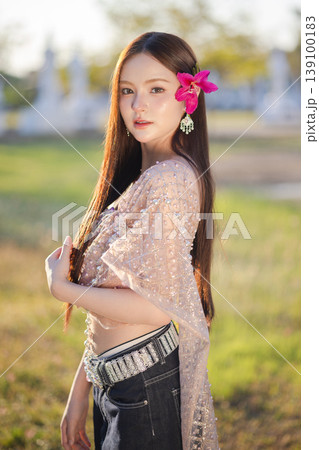 Trendy Thai fashion woman wearing a traditional Sabai paired with denim jeans at temple, reflecting the growing fashion trend in Thailand that blends cultural heritage with contemporary street style. 139100183