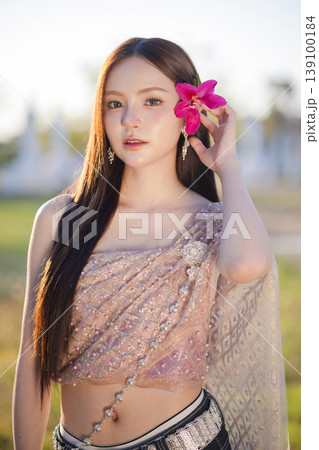 Trendy Thai fashion woman wearing a traditional Sabai paired with denim jeans at temple, reflecting the growing fashion trend in Thailand that blends cultural heritage with contemporary street style. 139100184