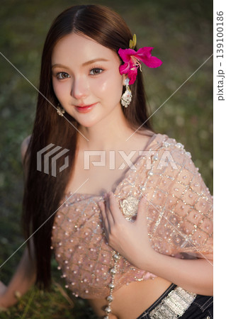 Trendy Thai fashion woman wearing a traditional Sabai paired with denim jeans at temple, reflecting the growing fashion trend in Thailand that blends cultural heritage with contemporary street style. 139100186
