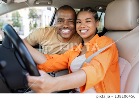 Smiling young African American couple sitting close inside car, expressing affection 139100456