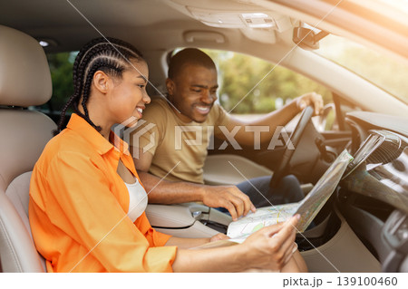 Young Black couple smiling while looking at paper map together in car 139100460