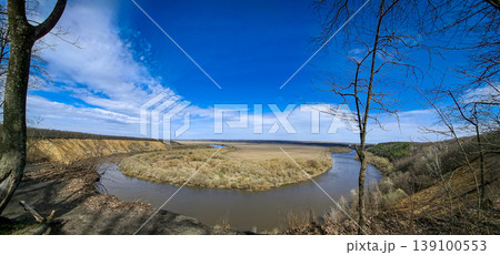 The Don River bending gently at the Krivoborye natural landmark in the Voronezh region. Bright blue sky stretches above the landscape and hills form the background. The Don River bending gently at the Krivoborye natural landmark in the Voronezh region. Bright blue sky stretches above the landscape and hills form the background. 139100553