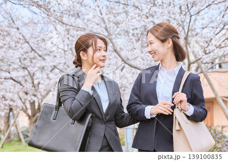 桜並木の下で会話する二人のリクルートスーツ姿の若い女性・春の就職活動イメージ 桜並木の下で会話する二人のリクルートスーツ姿の若い女性・春の就職活動イメージ 139100835