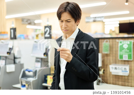 レシートの値段を見て不満を抱く男性 139101456