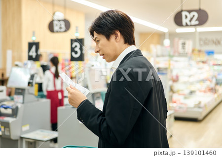 レシートの値段を見て不満を抱く男性 139101460