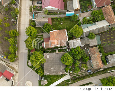 Aerial View Of Rural Village Rooftops Cluster Of Traditional Houses With Vegetable Gardens, Narrow Lanes, Trees And Orchards, Patchwork Plots And Hedges, Quiet Pastoral Atmosphere 139102542