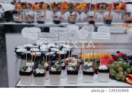 Modern Dessert Station With Layered Parfaits And Miniature Cups, Clear Glassware Filled With Mousse And Cream, Labeled Picks And Spoons, Chocolate Shavings And Berry Garnish, Sleek Table 139102668