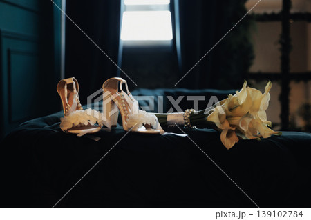 Ivory Bridal Shoes On Velvet Chaise, Cream Bouquet Beside Heels With Lace And Silk Ribbon Warm Window Light, Soft Shadows, Intimate Hotel Suite Morning, Bride Preparing Accessories, Vintage 139102784