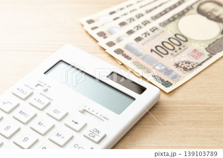 机に置かれた1万円札と電卓 139103789