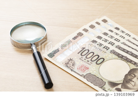 机に置かれた1万円札と虫眼鏡 139103969