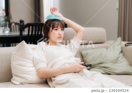 Exhausted asian woman resting at home feeling sick with severe headache taking break from work and study using technology holding ice pack on head showing pain 139104524
