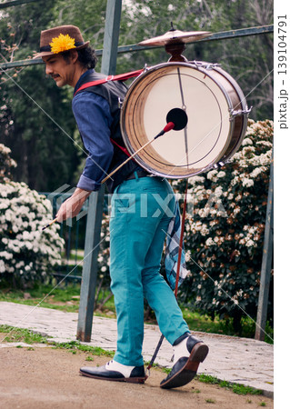 Adult man with a mustache, dressed formally and colorfully, posing and playing a bass drum on his back, Chilean chinchinero, street musician who plays the bass drum and dances in the streets Adult man with a mustache, dressed formally and colorfully, posing and playing a bass drum on his back, Chilean chinchinero, street musician who plays the bass drum and dances in the streets 139104791