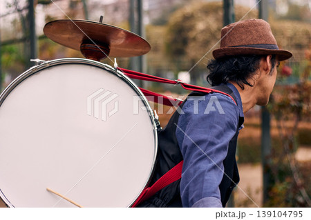 View of a bass drum with a cymbal on top, man playing bass drum on his back, Chilean chinchinero, street musician who plays the bass drum and dances in the streets, Chilean cultural tradition View of a bass drum with a cymbal on top, man playing bass drum on his back, Chilean chinchinero, street musician who plays the bass drum and dances in the streets, Chilean cultural tradition 139104795