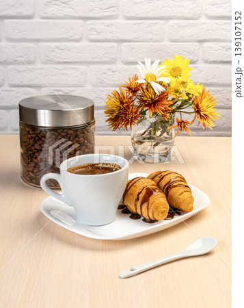 Cup of black coffee and fresh croissants on the white porcelain plate. Cup of black coffee and fresh croissants on the white porcelain plate. 139107152