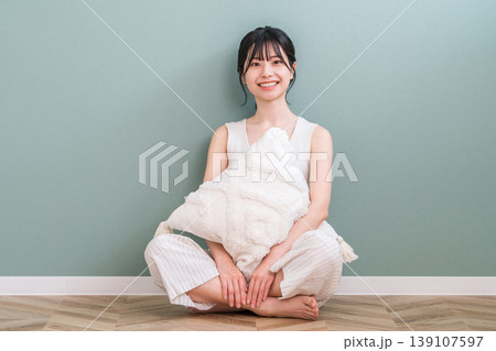 自宅のリビングでクッションを抱きながらくつろぐ笑顔の若いアジア人女性 139107597