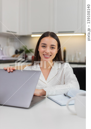 Young woman closes laptop looks at camera light smile breathes relief end of workday calm rest time 139108140