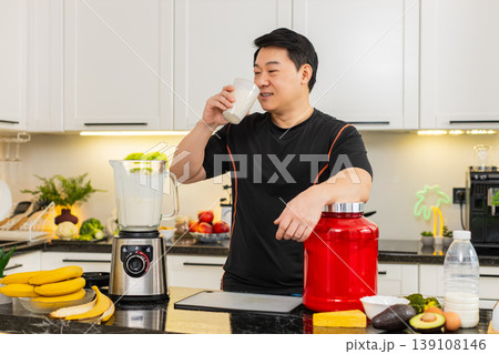 Asian man drinking protein banana cottage cheese shake in home kitchen after workout session routine 139108146