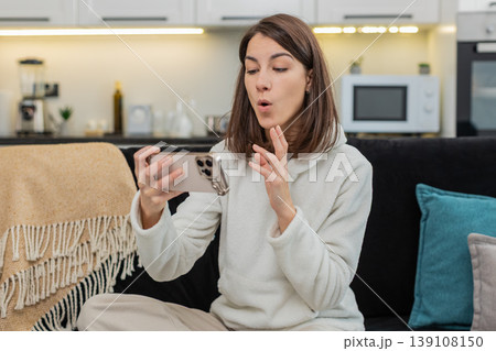 Young woman learns language on smartphone app repeats phrases earns high score smiles proud top mark Young woman learns language on smartphone app repeats phrases earns high score smiles proud top mark 139108150