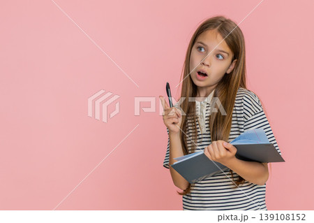 Child girl kid thoughtfully writing notes in notebook diary carefully planning detailed to-do list 139108152
