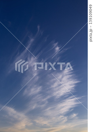 White cirrus uncinus clouds drifting in blue sky with golden sunset glow. White cirrus uncinus clouds drifting in blue sky with golden sunset glow. 139109049