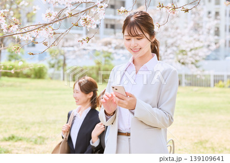 桜の下でスマートフォンを操作する笑顔の若い女性ビジネスパーソン・春の新生活イメージ 桜の下でスマートフォンを操作する笑顔の若い女性ビジネスパーソン・春の新生活イメージ 139109641