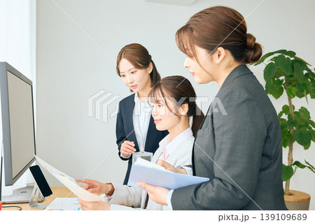 オフィスで資料を確認しながらパソコン画面を見る3人の女性ビジネスパーソン・チームワークで業務を進める 139109689