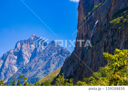 Majestic mountain peaks and waterfall under clear blue sky 139109830