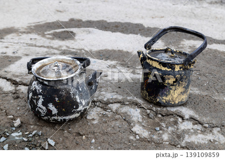 Burned vintage kettles on cracked dry ground Burned vintage kettles on cracked dry ground 139109859