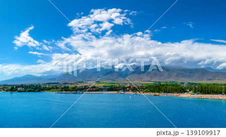 Vibrant beach scene at blue Issyk-Kul lake with parasailer 139109917