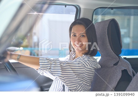 自動車の運転席でハンドルを握り、カメラ目線で微笑む日本人女性 139109940