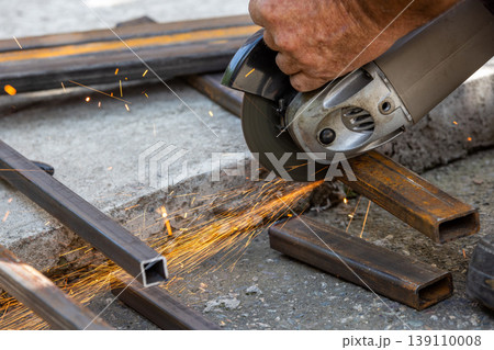 Close-up of angle grinder cutting metal bars outdoors Close-up of angle grinder cutting metal bars outdoors 139110008