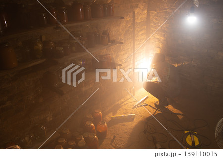 Person adjusting light in dimly lit cellar with preserves Person adjusting light in dimly lit cellar with preserves 139110015