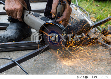 Angle grinder creating sparks while grinding metal bars outdoors Angle grinder creating sparks while grinding metal bars outdoors 139110029
