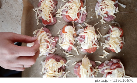 Cooking process of preparing food with cheese and toppings on a baking tray in a home kitchen 139110676