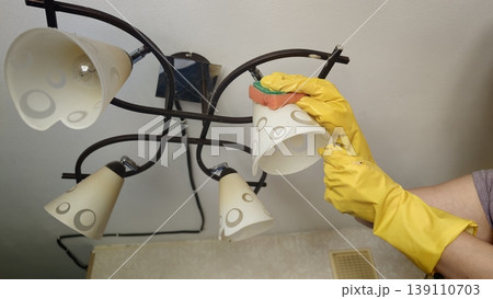 Cleaning light fixtures in a kitchen during daytime tasks to maintain cleanliness 139110703