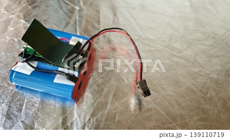 Battery connected to a circuit board and wires on a reflective surface for testing Battery connected to a circuit board and wires on a reflective surface for testing 139110719
