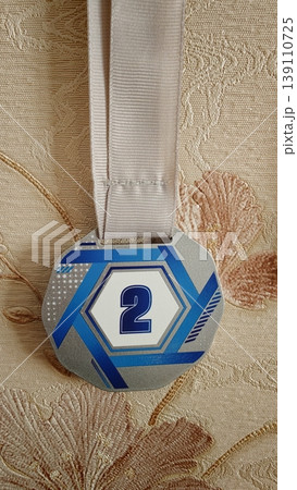 Award medal featuring number two hanging on a beige background at home Award medal featuring number two hanging on a beige background at home 139110725