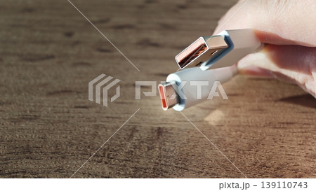 USB cable held in hand showing both USB-A and USB-C connectors on wooden surface USB cable held in hand showing both USB-A and USB-C connectors on wooden surface 139110743