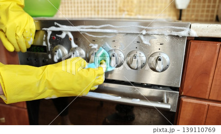 Cleaning the stove with soap and sponge in a kitchen during the day 139110769
