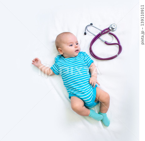 Newborn little baby lies on a white bed near stethoscope before seeing a pediatrician. Caring for a child's health in the clinic 139110911
