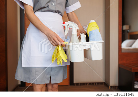 Close up of hotel maid holding cleaning caddy with gloves and detergents 139111649