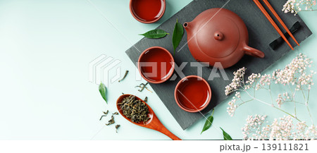 Red Clay Teapot and Teacups with Green Tea Leaves and Flowers Red Clay Teapot and Teacups with Green Tea Leaves and Flowers 139111821