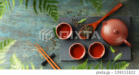 Traditional Asian Tea Ceremony with Red Clay Teapot and Loose Leaf Tea on Rustic Surface 139111822