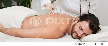 Male patient with acupuncture needles inserted in his back is receiving treatment chronic back pain in a traditional Chinese medicine clinic with acupuncturist Male patient with acupuncture needles inserted in his back is receiving treatment chronic back pain in a traditional Chinese medicine clinic with acupuncturist 139111918