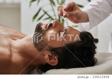 Acupuncturist inserts acupuncture needles into acupuncture point on male head for headaches. Traditional chinese medicine, reflexology Acupuncturist inserts acupuncture needles into acupuncture point on male head for headaches. Traditional chinese medicine, reflexology 139111939