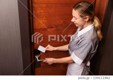 Female hotel housekeeper opening room door with electronic keycard system 139111962